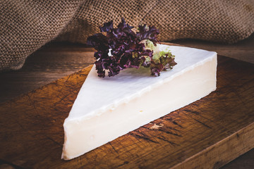portion of brie cheese camenbert on wood cutting board