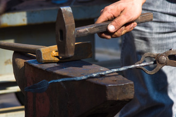 blacksmith performs the forging of hot glowing metal on the anvil