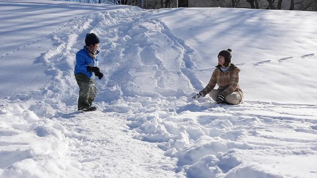 Asian mother and her son playing snow together in the park , sapporo japan slow motion 