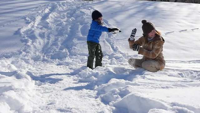Asian mother and her son playing snow together in the park , sapporo japan slow motion 