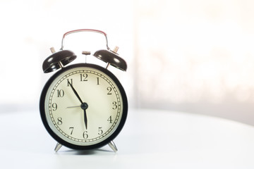 Black alarm clock on white table background