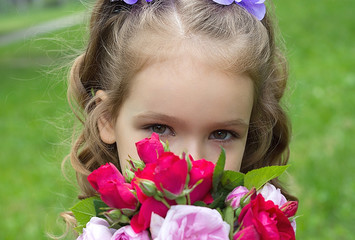 Child girl with bouquet of roses. Focus on the girl eyes
