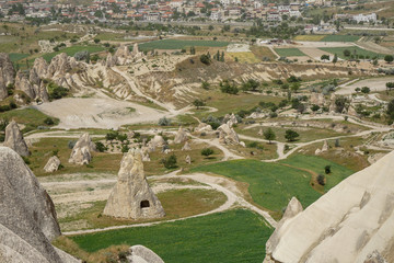 Beautiful inspiring scenic panoramic landscape view of rock cave from red valley with Goreme town background, selective focus, Cappadocia