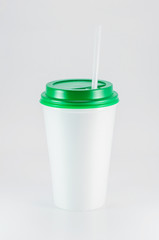 white plastic coffee cup with green lid on white background, view from above with copy space