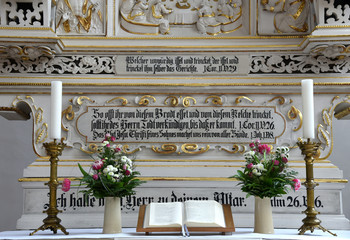Fototapeta premium Altar mit aufgeschlagener Bibel, Kerzenleuchtern und Blumen im Dom St. Petri zu Bautzen