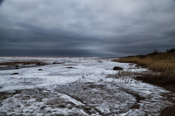 landscape with frozen sea, sandy beach and dry grass on it