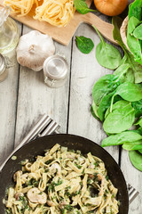 Tagliatelle pasta with spinach and mushrooms on a pan.