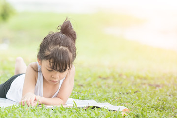 child is lying on the grass with phone. Girl playing with a digital phong or watching a movie or listening to music outdoors. view from above