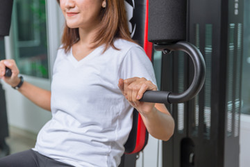 Obraz premium Young woman in the gym training chest muscle machine