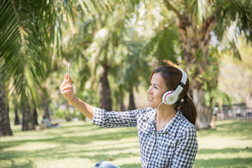 Beautiful girl sitting in the park and makes selfie