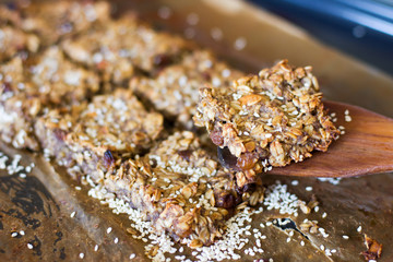Dietary oatmeal cookies with raisins, nuts and sesame seeds on parchment with parchment laid portionwise. Proper nutrition. The food is healthy