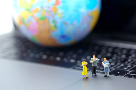 Miniature people : reading book on laptop with globe world map, education or business concept.