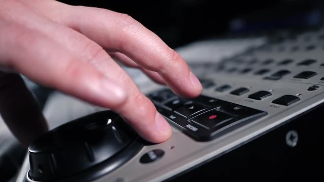 Sound engineer rotates the scroll wheel on mixing console in a professional recording studio. Musician working on new song. Slow motion.
