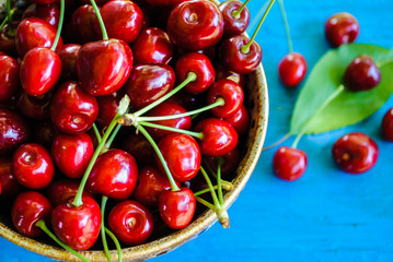 Red cherries in a plate on a blue background