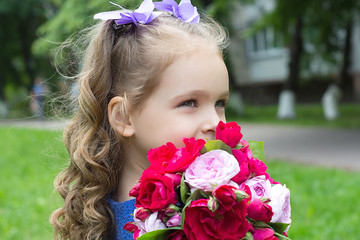 Child girl with bouquet of roses. Focus on the girl