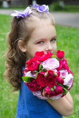 Child girl with bouquet of roses. Focus on the girl