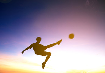 Fototapeta na wymiar Silhouette of soccer player kicks ball with sunset background