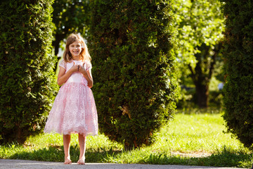 Portrait of a cheerful girl in a lush pink dress in the park.