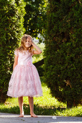 Portrait of a cheerful girl in a lush pink dress in the park.