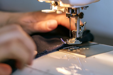 Girl sews a suit of blue cloth with the sewing machine - obrazy, fototapety, plakaty