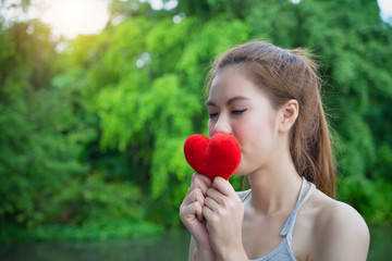 Portrait young beautiful girl kissing red heart..Model woman with red heart..Lovely face female kiss love symbol and heart sign in outdoor nature..charming people lifestyle