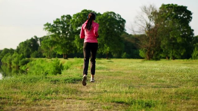 A morning jog in the Park near the pond in the Sunny rays of dawn, the girl is preparing to Mariano and lead a healthy lifestyle