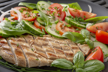 Vegetable salad and grilled chicken on a black background. Healthy food. Diet.