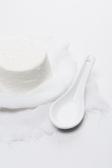 delicious cottage cheese on cheesecloth with spoon on white tabletop