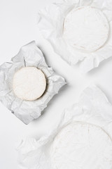 top view of organic brie cheese heads on crumpled paper and on white surface