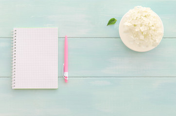 Open notebook with pink pen, coffee cup and hydrangea