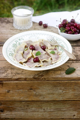 Vegetarian dumplings with cherries served with sugar. Rustic style.
