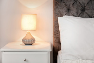 Lamp on bedside table in modern hotel room