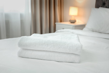 Stack of towels on bed in modern hotel room