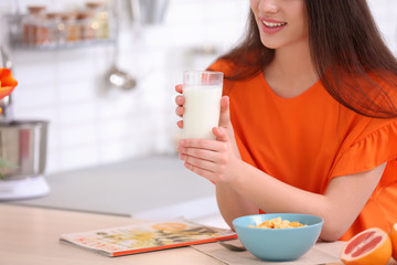 Beautiful young woman drinking milk at table