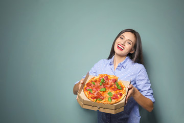 Attractive young woman with delicious pizza on color background