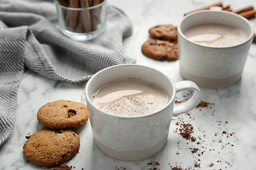 Cookies and cups with delicious hot cocoa drink on table