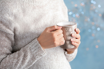 Young woman with delicious hot cocoa drink on blurred background, closeup