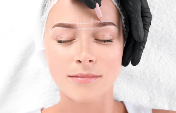 Young woman undergoing eyebrow correction procedure in salon, top view
