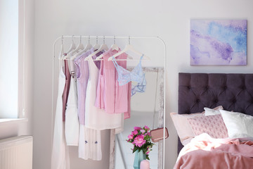 Stylish bedroom interior with clothes rack and mirror