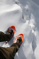 Reckless hiker with orange snowshoes and velvet pants on the edg