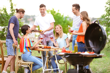 Young people having barbecue with modern grill outdoors