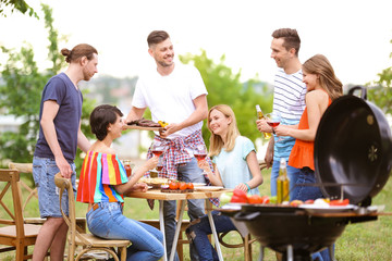 Young people having barbecue with modern grill outdoors