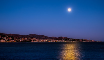 Fototapeta premium The moon over the sea and Malaga city, Spain
