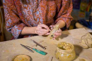 Woman potter making ceramic souvenir penny whistle in pottery workshop