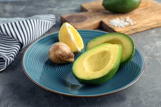 Plate with ripe avocado and lemon on table