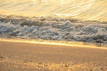 Waves sandy beach during golden sunset