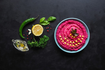 Hummus with beetroot on a black kitchen table.