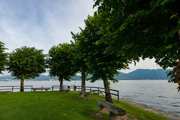 Cannobbio, Italy, June 10, 2016 - Lakeside Park with two people near the water, Lago Maggiore, Beach of Cannero Riviera