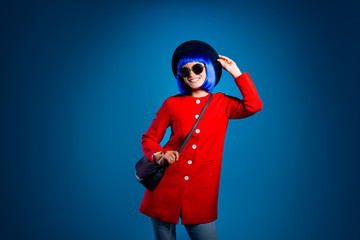 Portrait of cheerful fancy girl in red coat pants having beaming smile resting relaxing posing holding bag on shoulder isolated on vivid blue background