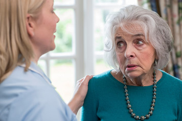 Care Worker Talking To Depressed Senior Woman At Home
